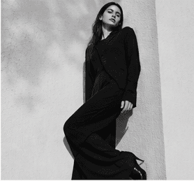 Monochrome fashion portrait in a dark tailored silhouette.