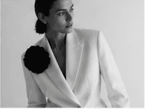 Black-and-white tailored portrait with floral lapel detail.